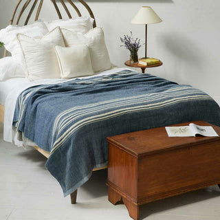 White blanket with blue stripes on bed