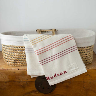 white baby blanket in basket with stripes